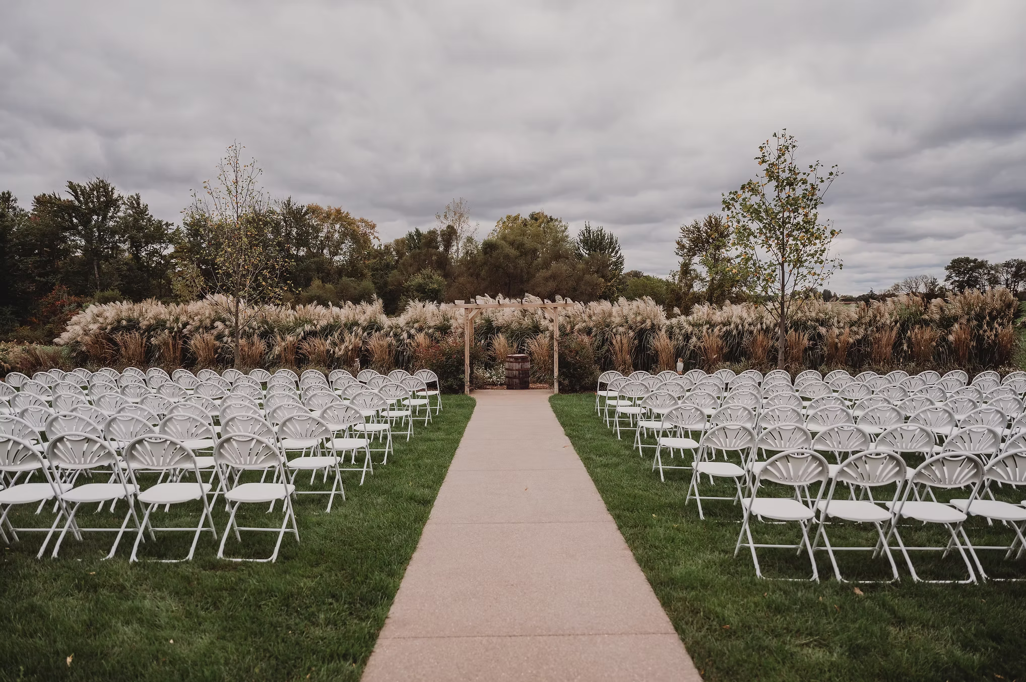 White ceremony chairs in rows on a green lawn.