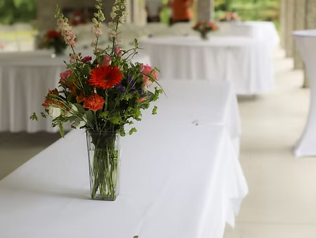 Folding tables draped in white linens with floral centerpieces.