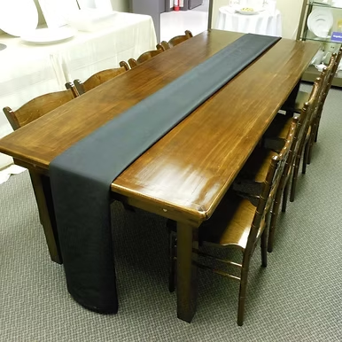Walnut farm table with black runner and matching wood chairs.